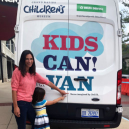Jodi Rector, winner of the GRCM contest to name the van, pointing to her name on the back of the van.